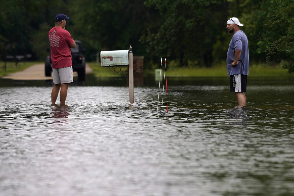Danny Gonzales, right, stands in front of his flooded house with his neighbor Bob Neal, upset w ...