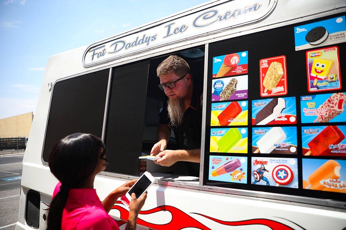 Al Davis, owner of Fat Daddy's Ice Cream truck, hands ice cream to Jazmine Eady outside Caliber ...