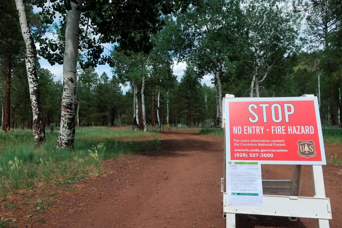 A sign posted ahead of a forest road announces the closure of the national forest surrounding F ...