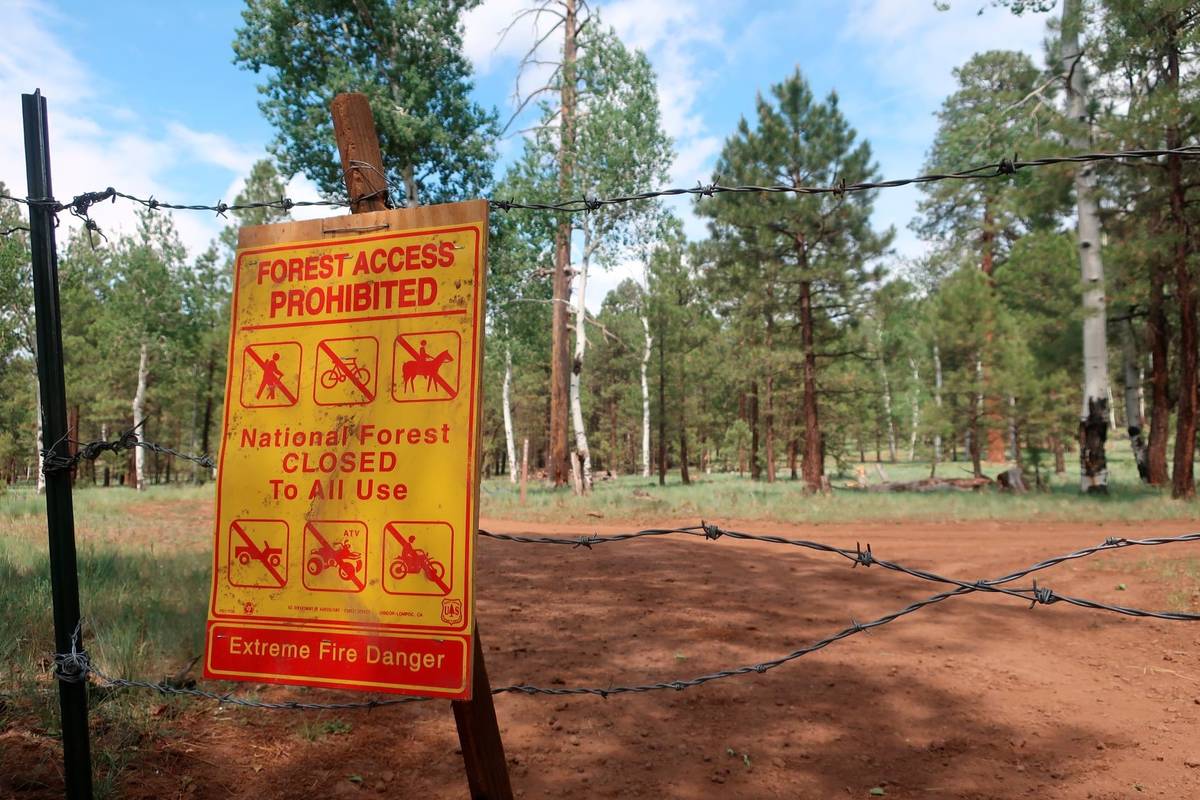 A sign warning of the closure of the national forest surrounding Flagstaff, Ariz., hangs on bar ...