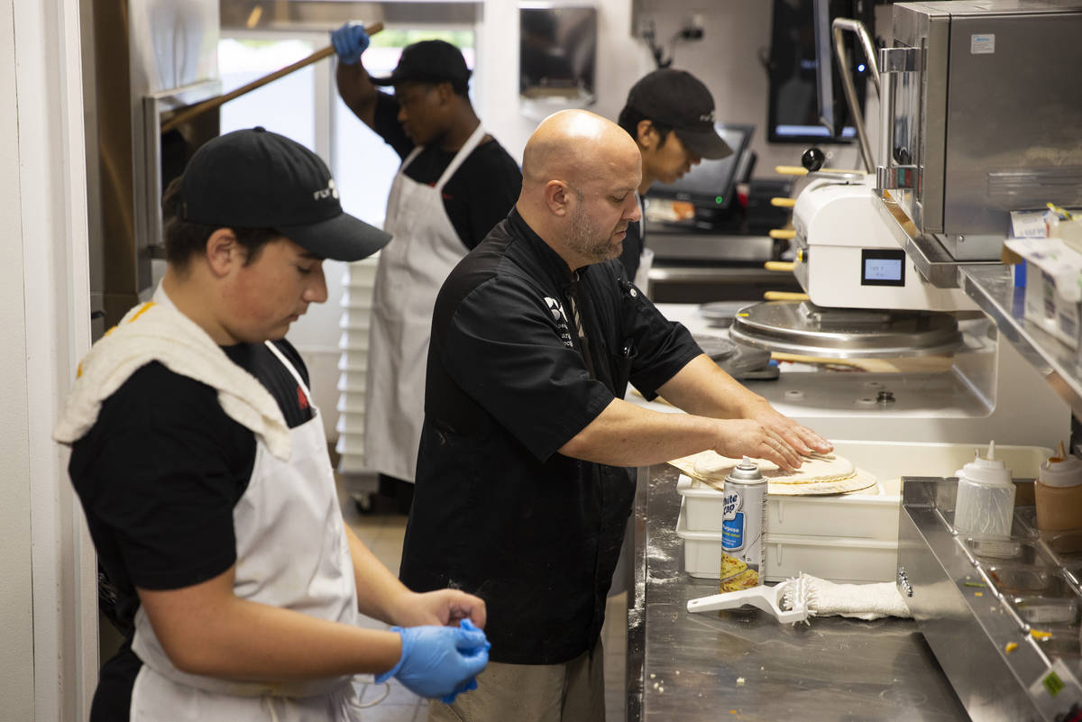 Executive chef Aaron Raeder, center, trains crew members in the kitchen of Fly Pie pizza drive- ...