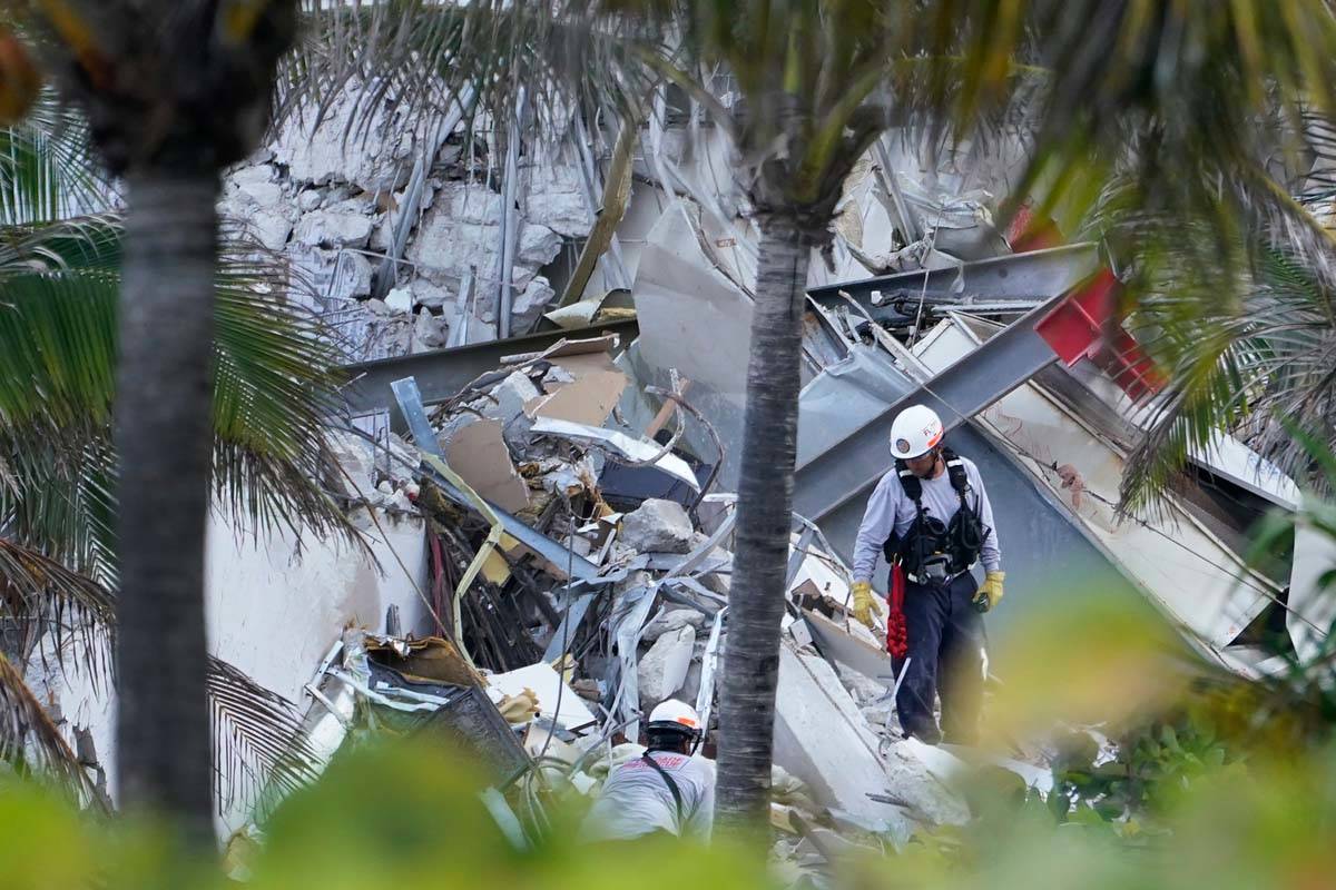 Rescue workers walk among the rubble where part of a 12-story beachfront condo building collaps ...