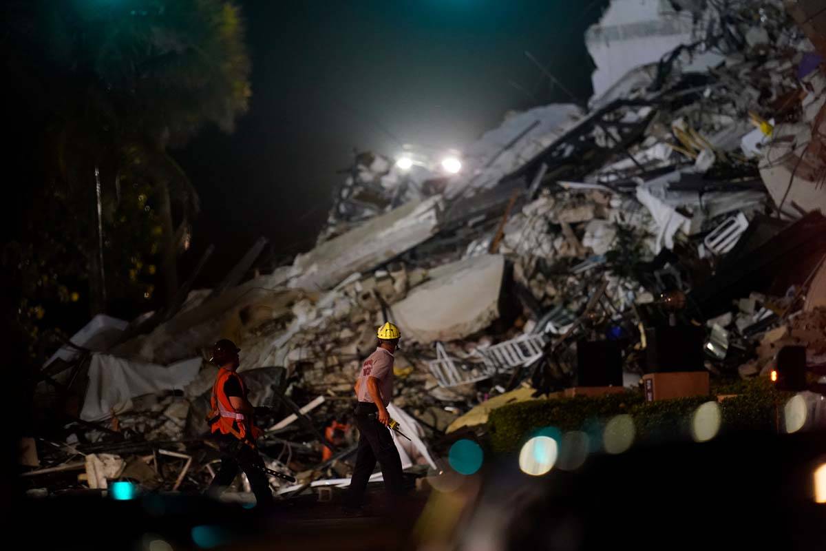 Rescue workers walk beside the rubble as rescue efforts continue where a wing of a 12-story bea ...