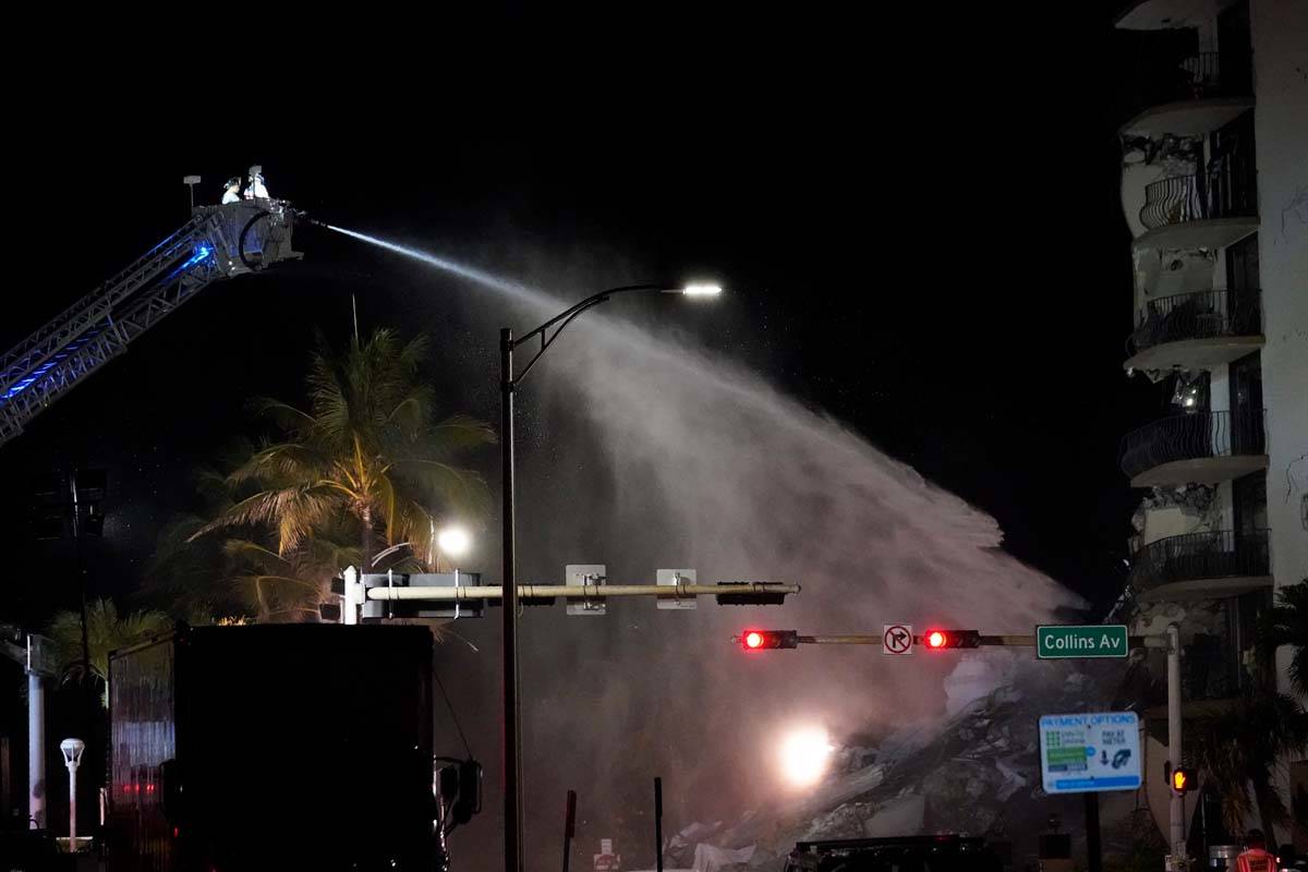 A Miami-Dade Fire Rescue team sprays water onto the rubble as rescue efforts continue where a w ...