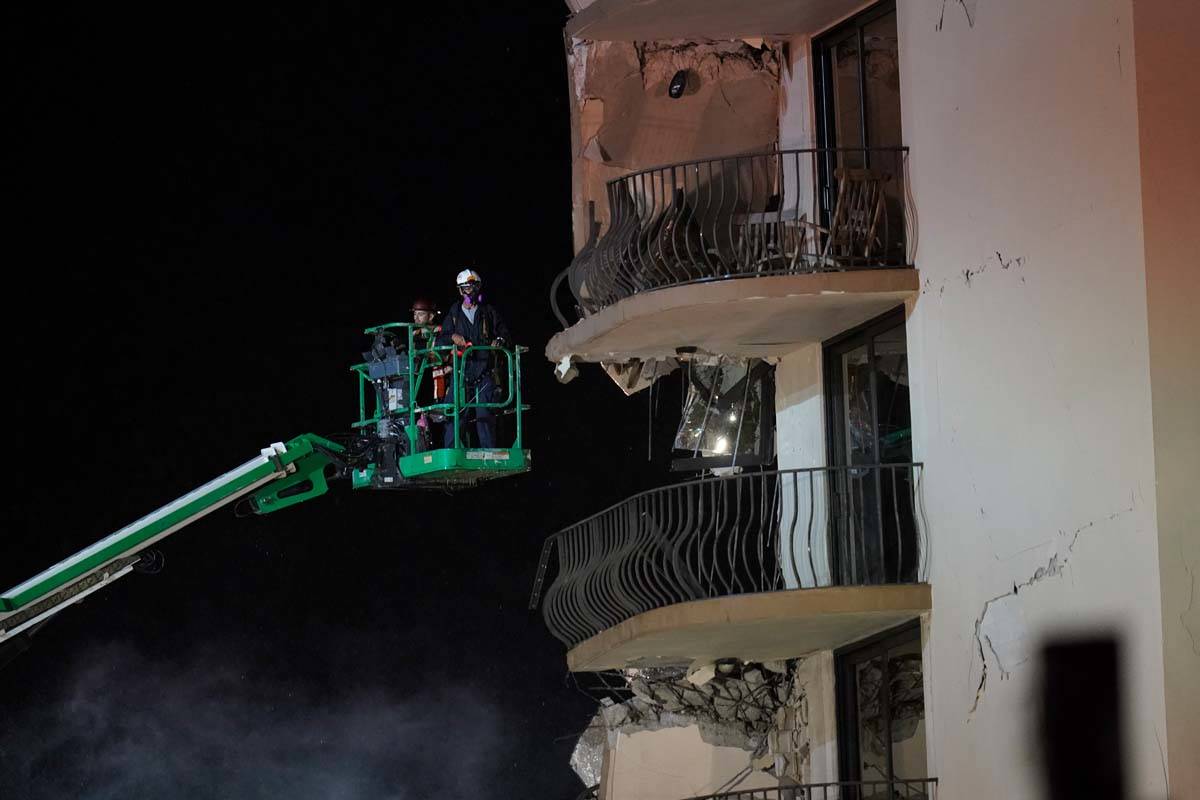 Workers use a lift to investigate balconies in the still-standing portion of the building, as r ...