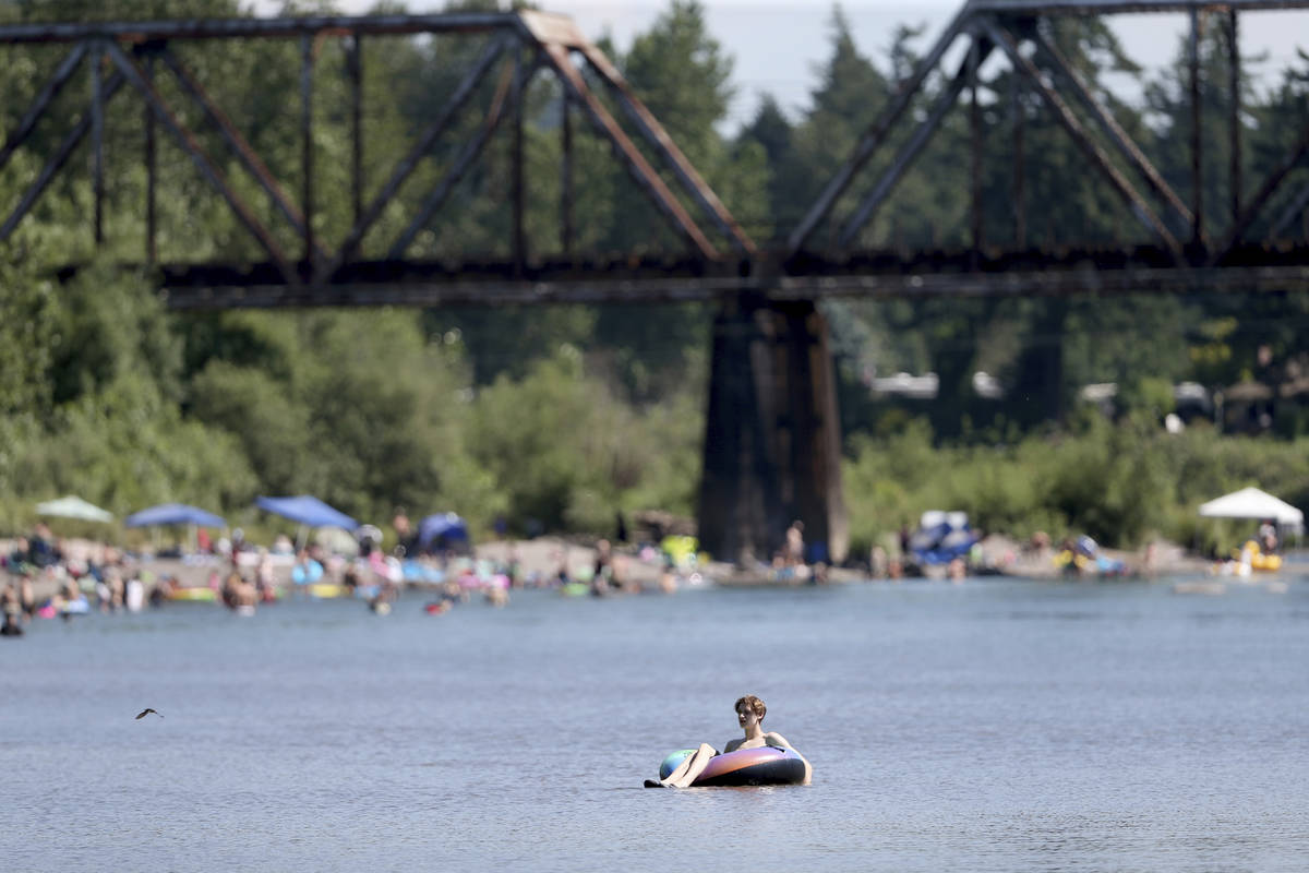 People gather at the Sandy River Delta, in Ore., to cool off during the start of what should be ...
