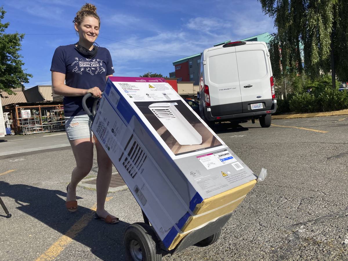 Sarah O'Sell transports her new air conditioning unit to her nearby apartment on a dolly in Sea ...