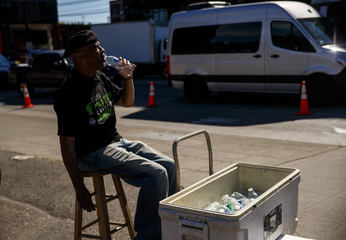 Carl Goodwin, manager of Seattle Sausage, takes a water break while selling bottles of water to ...