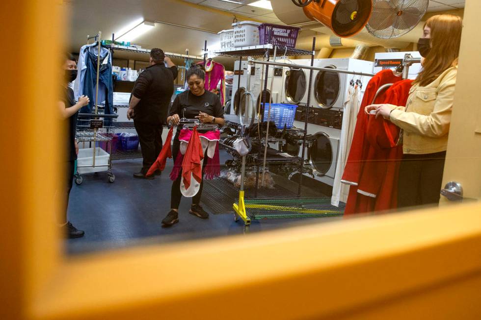 Wardrobe staff readies costumes downstairs while a rehearsal for "O" is underway upst ...