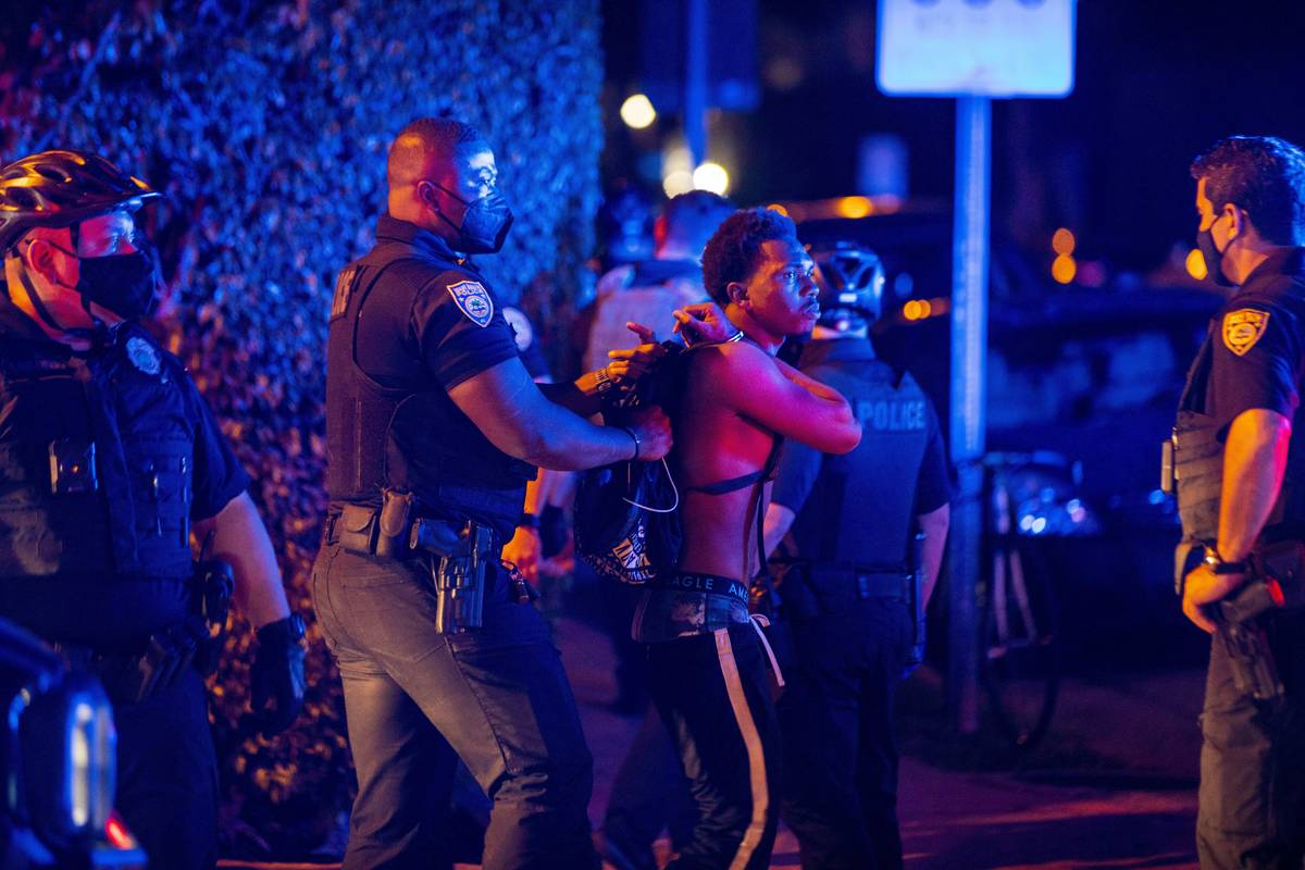 A man is arrested while out a few hours past curfew in Miami Beach, Fla., on Sunday, March 21, ...