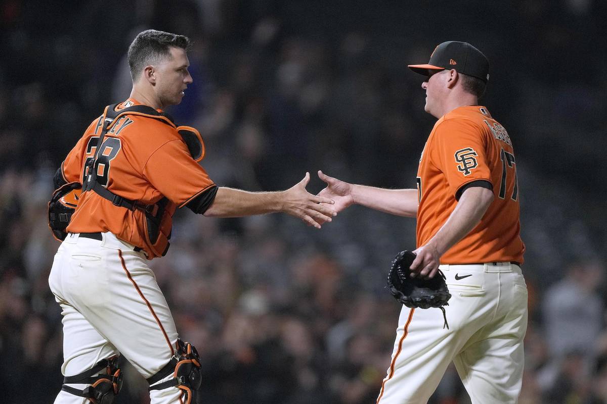San Francisco Giants relief pitcher Jake McGee (17) shake hands with catcher Buster Posey after ...