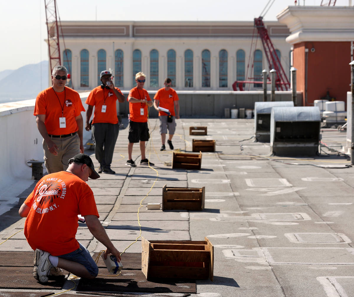 Fireworks by Grucci pyrotechnicians lay wiring on the roof of Treasure Island on the Strip in L ...