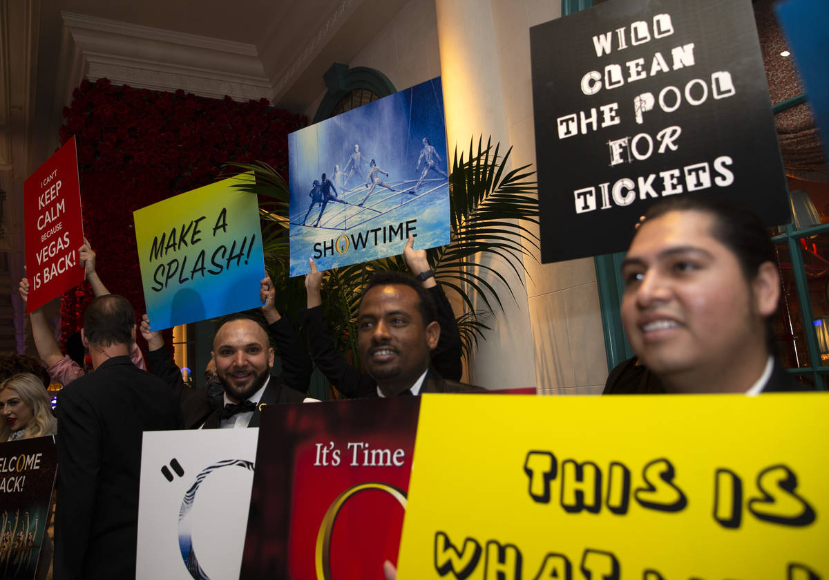 Bellagio employees hold signs alongside a welcome back parade for Cirque du Soleil show "O ...