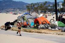 A jogger walks past a homeless encampment in the Venice Beach section of Los Angeles in June 20 ...