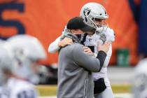 Raiders head coach Jon Gruden, left, hugs Raiders quarterback Derek Carr (4) during warm ups be ...