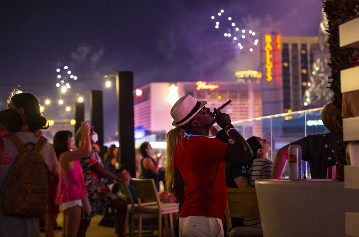 A man smokes a cigar while watching fireworks go off along the Las Vegas Strip from the Bouleva ...