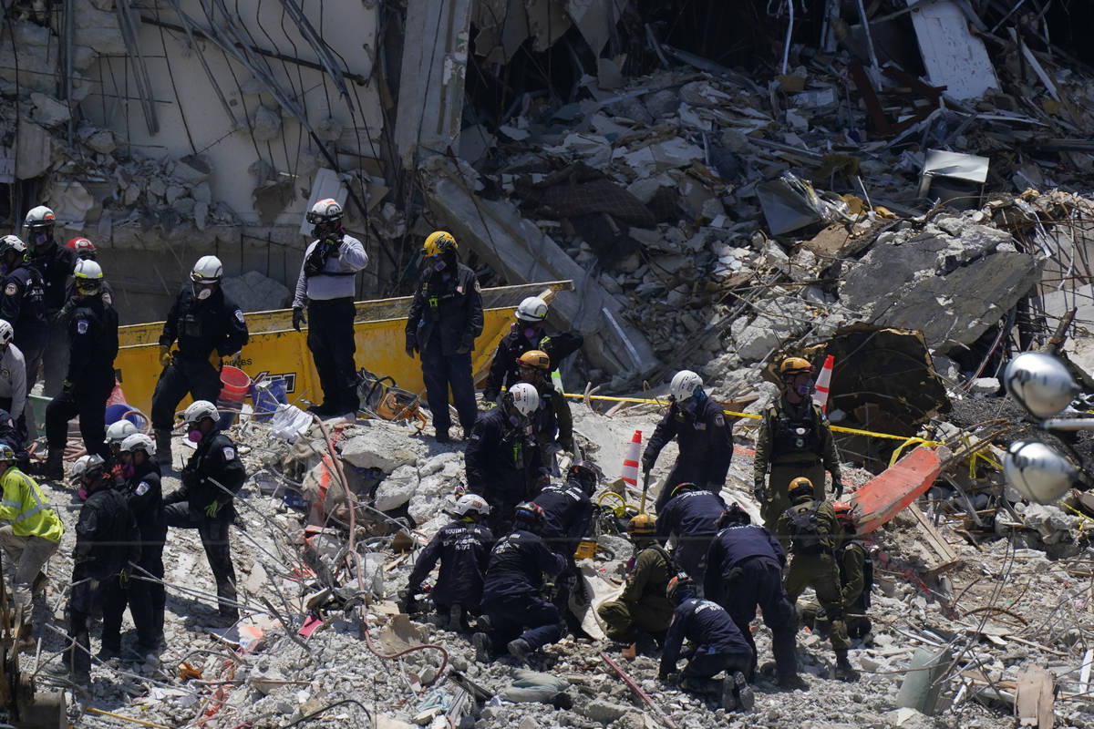 Search and rescue personnel work atop the rubble at the Champlain Towers South condo building, ...