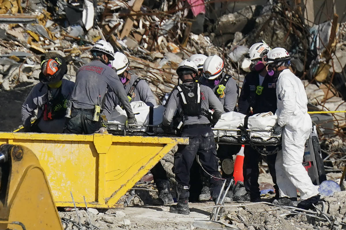 Search and rescue personnel remove remains on a stretcher as they work atop the rubble at the C ...