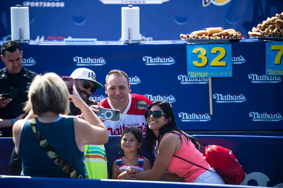 Winners Joey Chestnut and Michelle Lesco, obscured behind hot dogs, pose at the Nathan's Famous ...