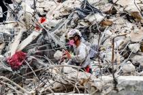 A search and rescue team member moves through the rubble of the Champlain Towers South condo, W ...