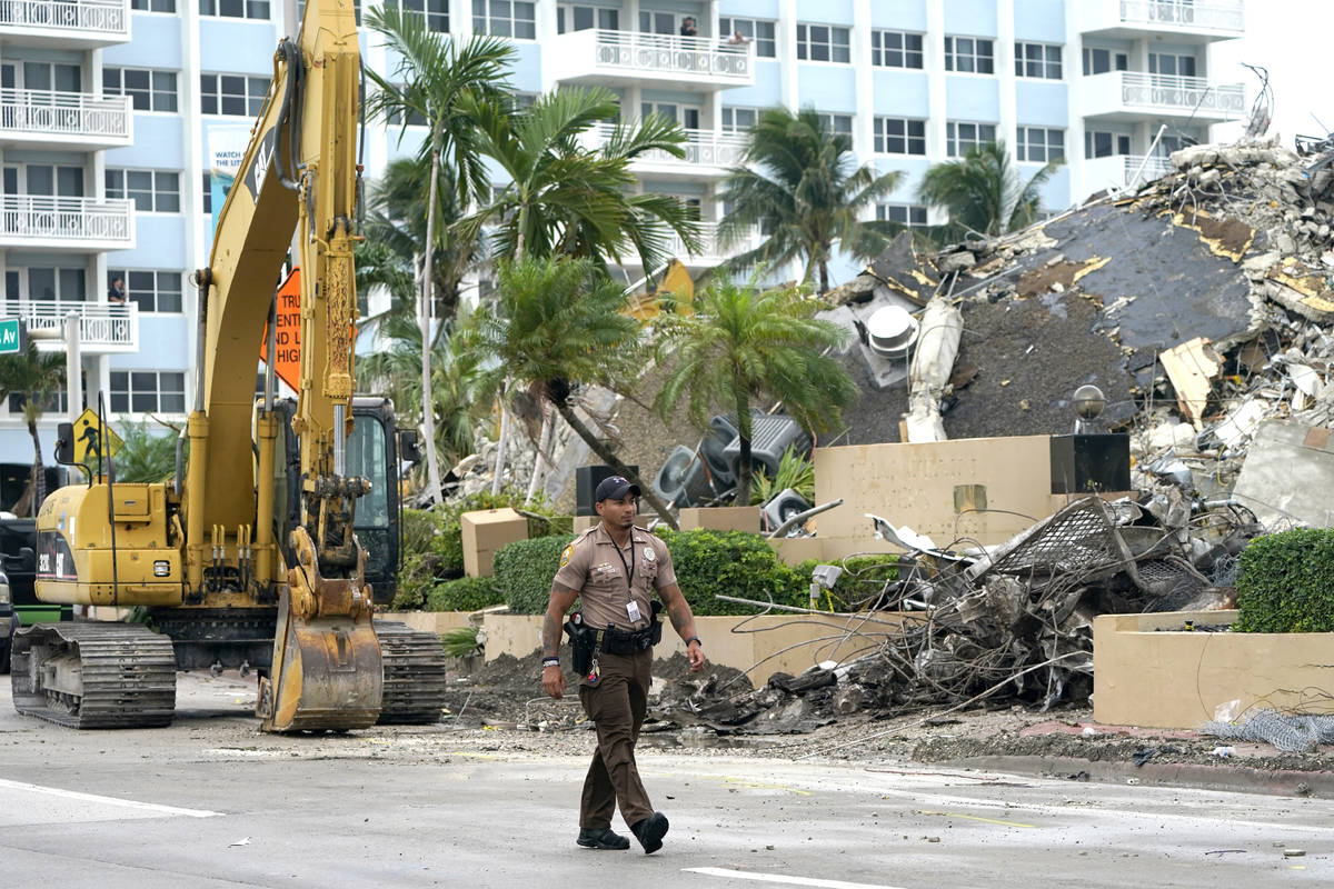 A police officer walks past the collapsed and demolished Champlain Towers South condominium bui ...