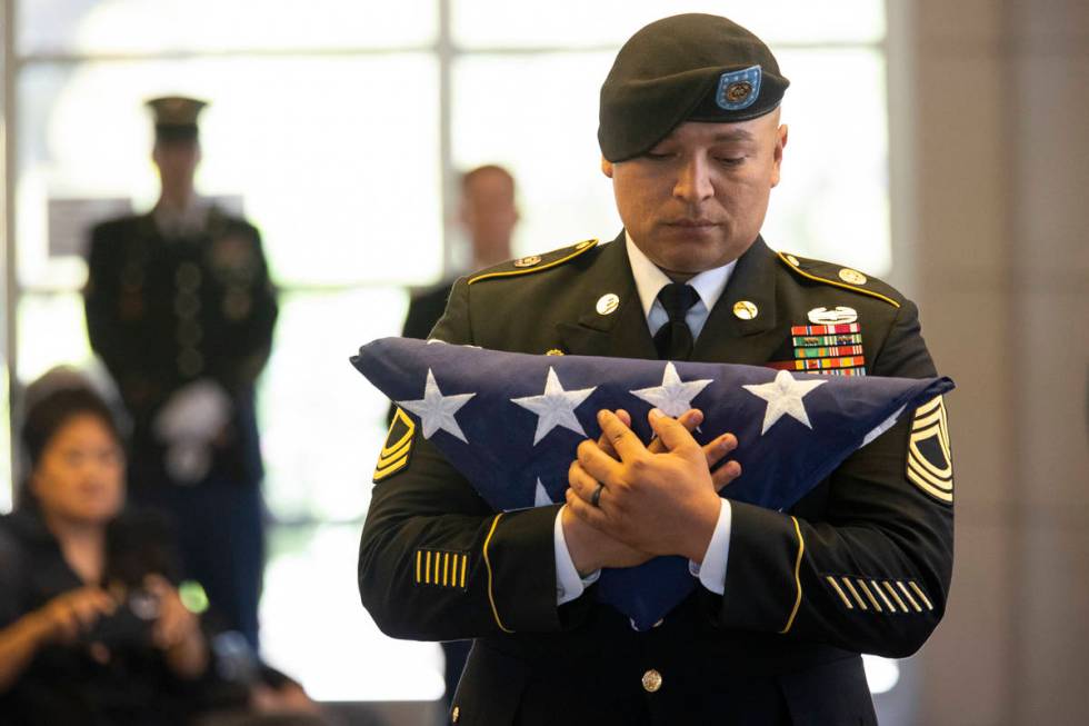 U.S. Army Master Sgt. Rafael Aguilera holds the American flag before presenting it to the famil ...