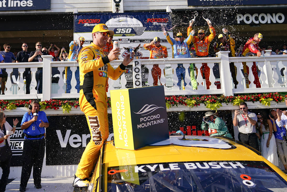 Kyle Busch celebrates with teammates after winning a NASCAR Cup Series auto race at Pocono Race ...