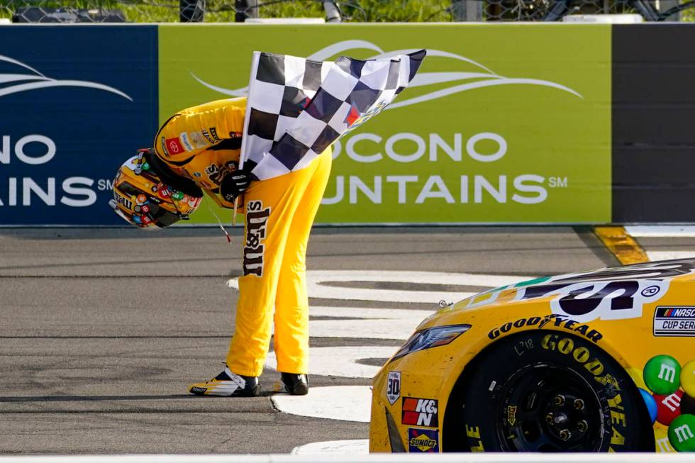 Kyle Busch takes a bow with the checker flag after winning a NASCAR Cup Series auto race at Poc ...