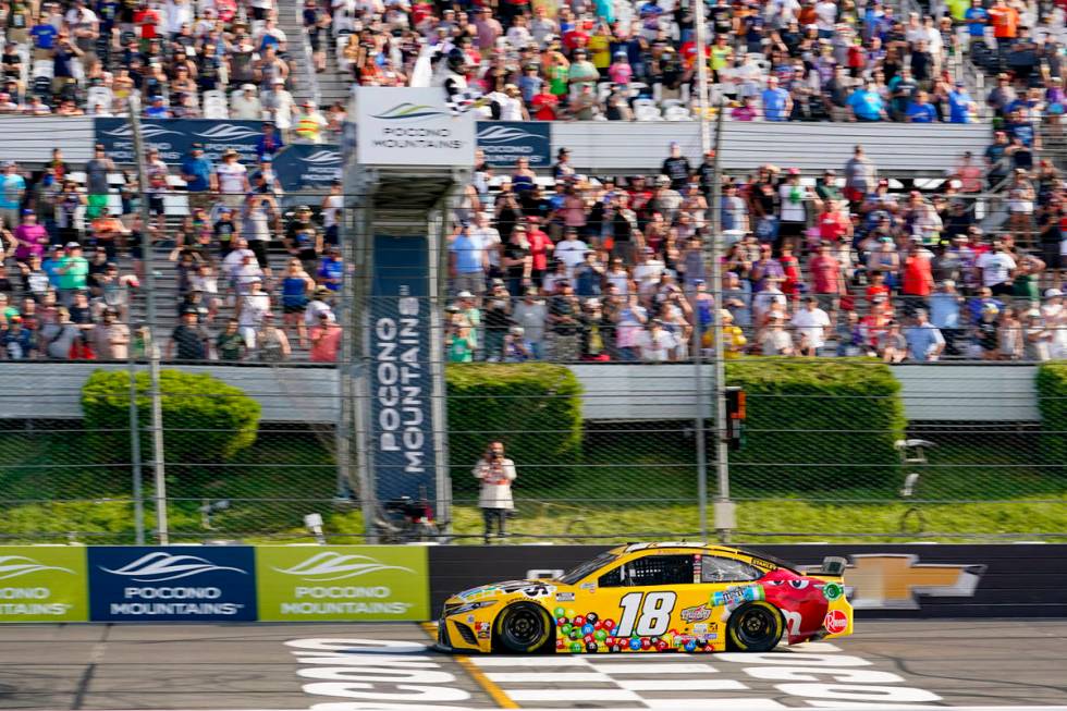 Kyle Busch (18) takes the checker flag to win the NASCAR Cup Series auto race at Pocono Raceway ...
