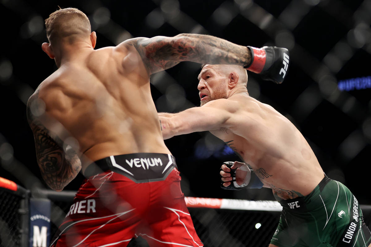 Conor McGregor, right, throws a punch against Dustin Poirier in the first round of a lightweigh ...