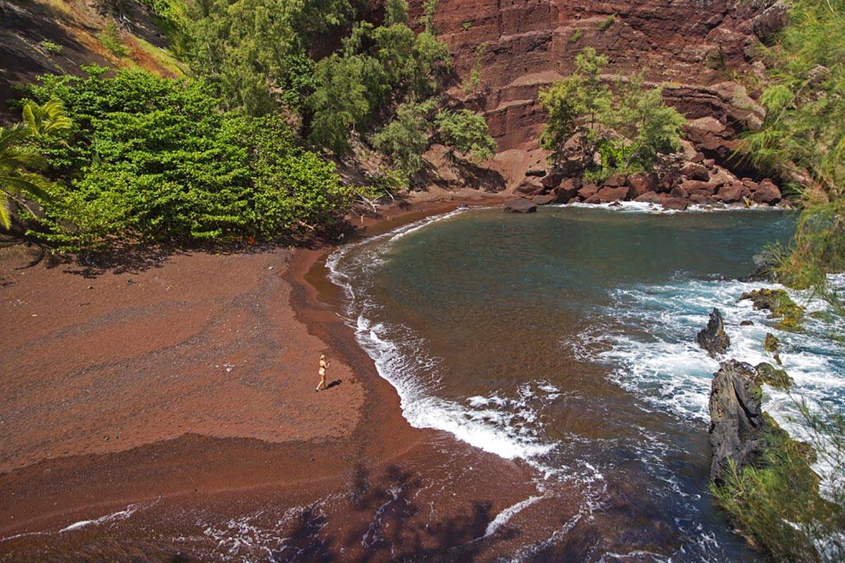 FILE - In this Sept. 24, 2014, file photo, a woman walks on the red sand beach at Kaihalulu Bay ...