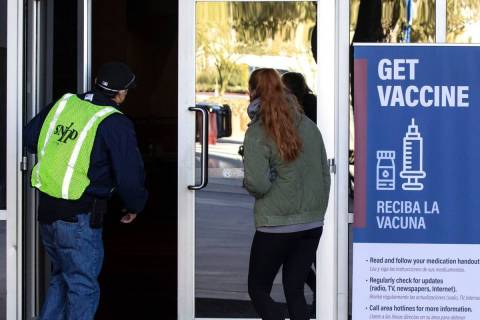 A FEMA volunteer leads a woman into the Las Vegas Convention Center's vaccine distribution area ...