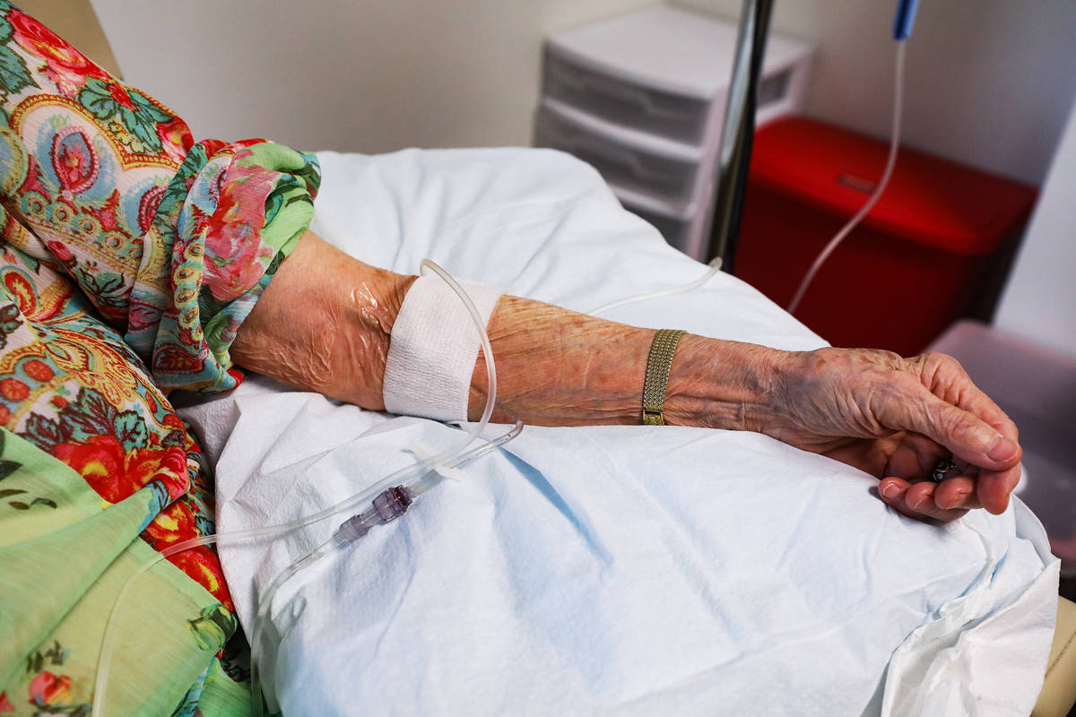 Judy Robinson’s arm shows the infusion of aducanumab, a drug designed by Biogen to slow ...