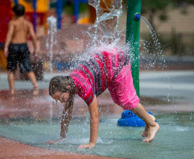 Ellie Bagenski, 7, of Baker City, Oregon, is pounded with water on the splash pad at Bob Baskin ...