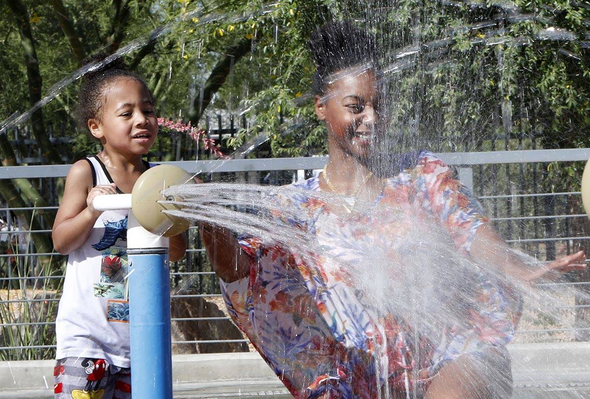 Diamond Cook of Las Vegas plays with her son Lincoln Carter, 3, in the splash pad at Baker Park ...
