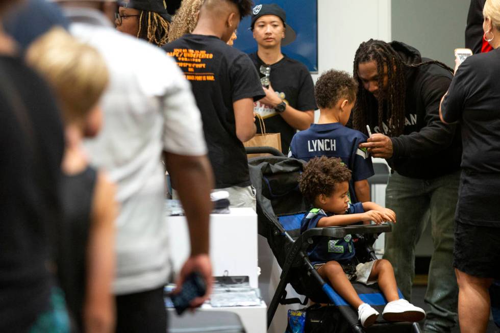 NFL running back Marshawn Lynch signs a jersey for Romeo Havard, 5, among fans and customers at ...