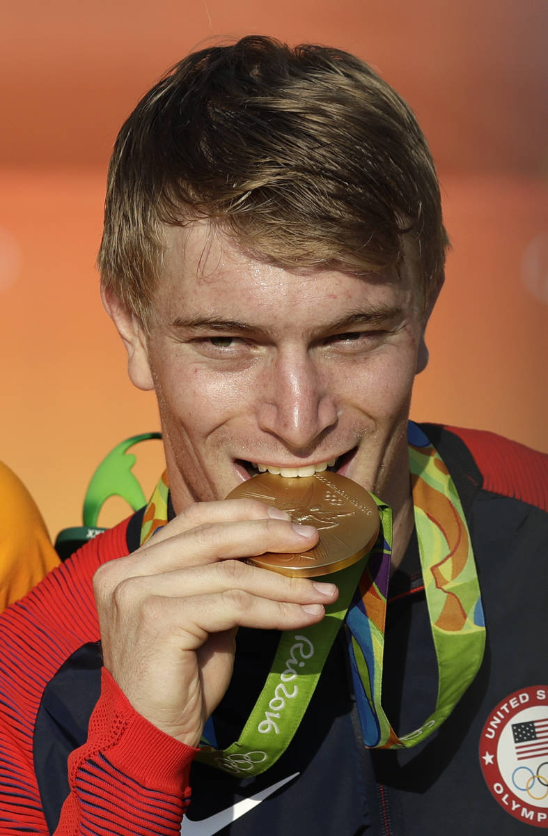 Connor Fields of the United States bites his gold medal on the podium ceremony of the men's BMX ...