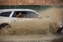 Cars move through a flooded portion of Buffalo Drive near Post Road in Las Vegas on Wednesday, ...