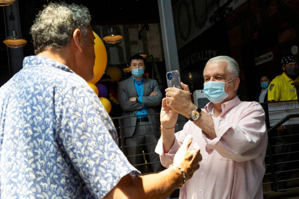 Gov. Steve Sisolak takes a video of comedian Brad Garrett during a pop-up vaccination clinic ho ...