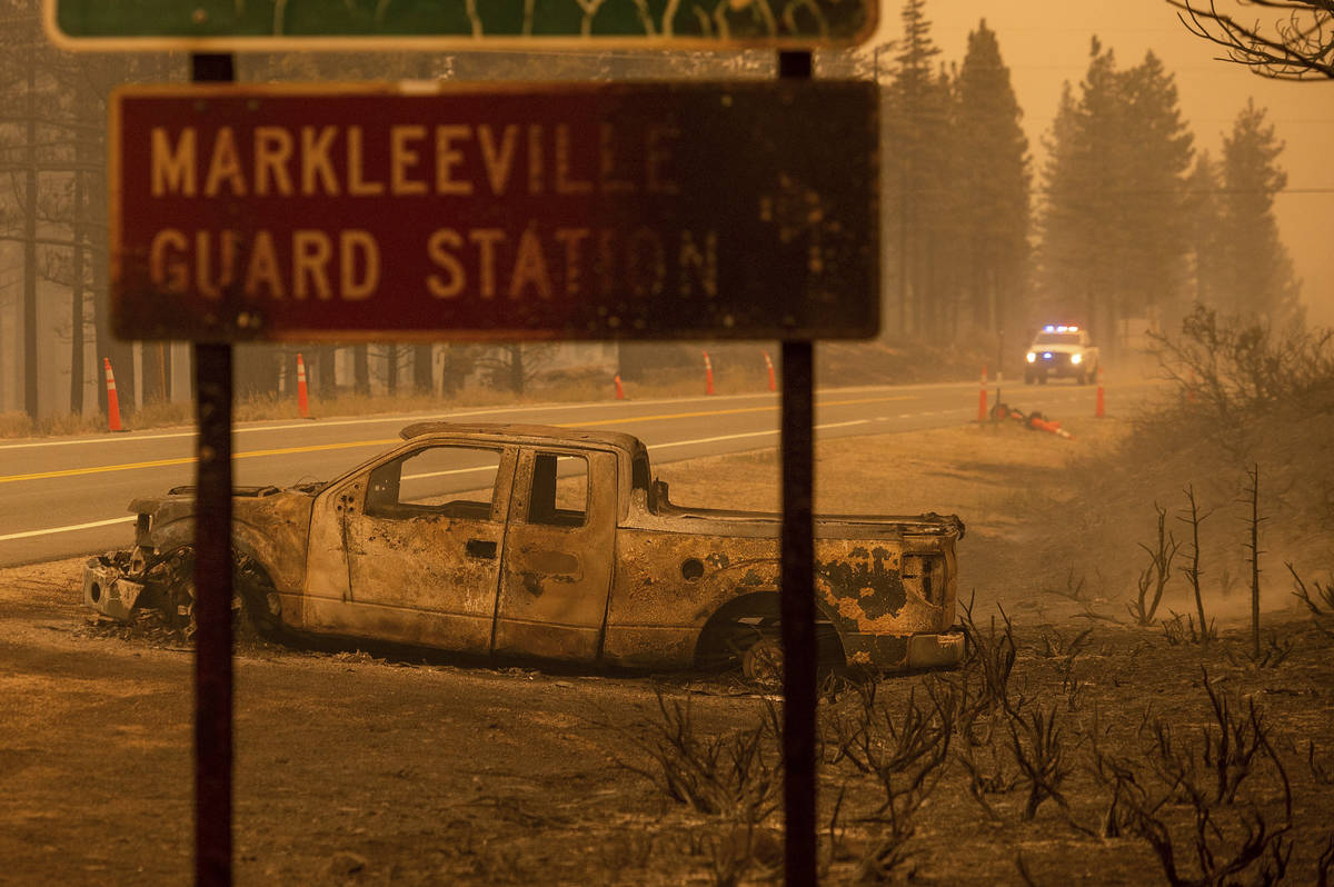 A scorched car rests on a roadside as the Tamarack Fire burns in the Markleeville community of ...