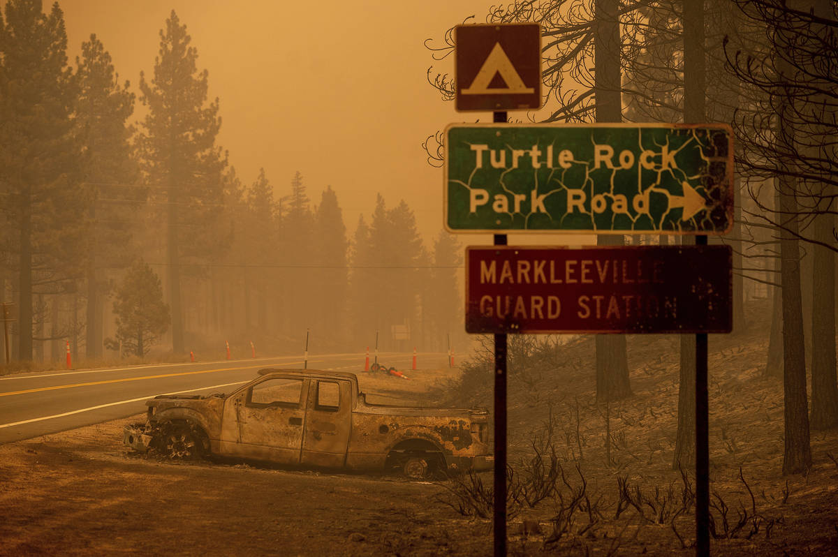 A scorched car rests on a roadside as the Tamarack Fire burns in the Markleeville community of ...