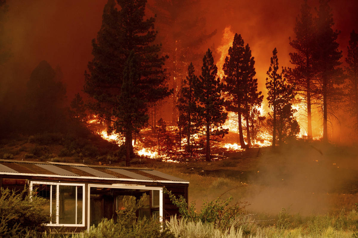 The Tamarack Fire burns behind a greenhouse in the Markleeville community of Alpine County, Cal ...