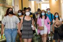 In this July 1, 2021, file photo visitors wear masks as they walk in a shopping district in the ...