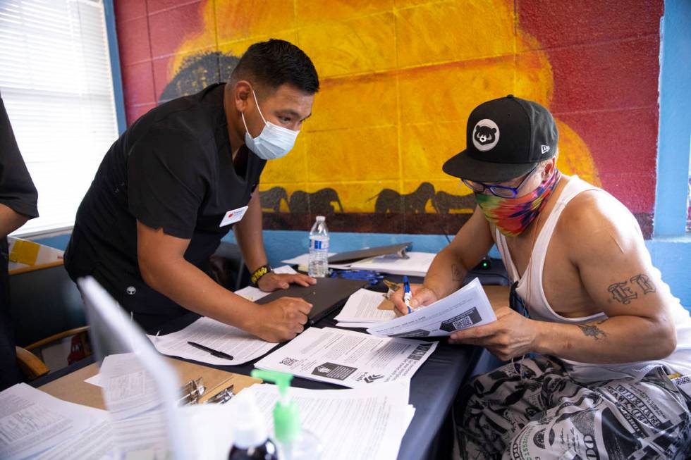 Francisco Ortiz, left, with Impact Health, assists Dino Poston with his intake information for ...