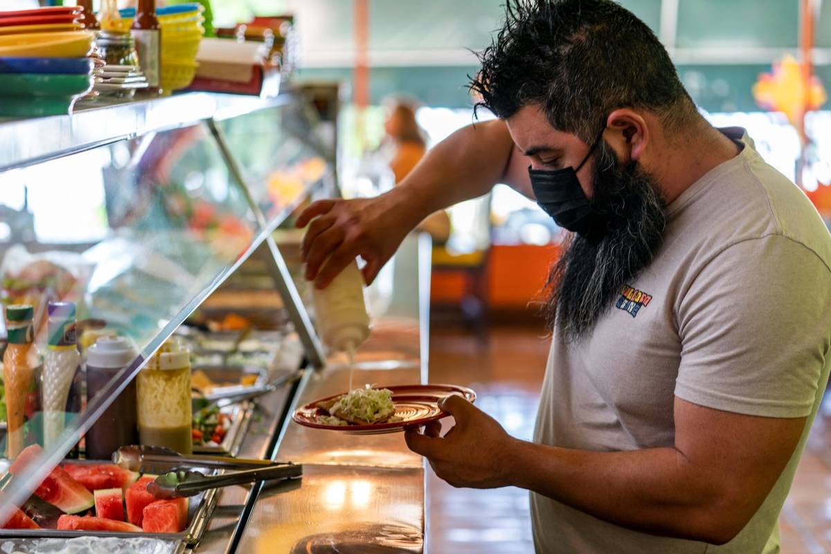 Gustavo Arellano, 36, who is vaccinated, wears a face mask as he fixes himself a plate at Taque ...
