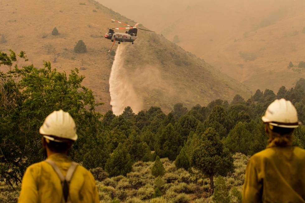 A firefighting helicopter drops water as the Tamarack Fire burns around Topaz Lake, Nev., Frida ...