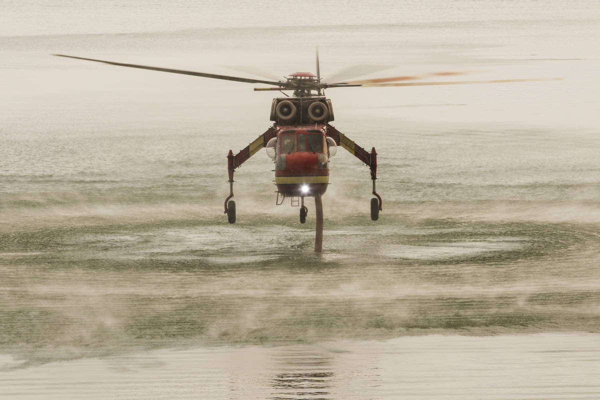 A firefighting helicopter is seen at Topaz Lake, in Nevada, Friday, July 23, 2021, while the T ...