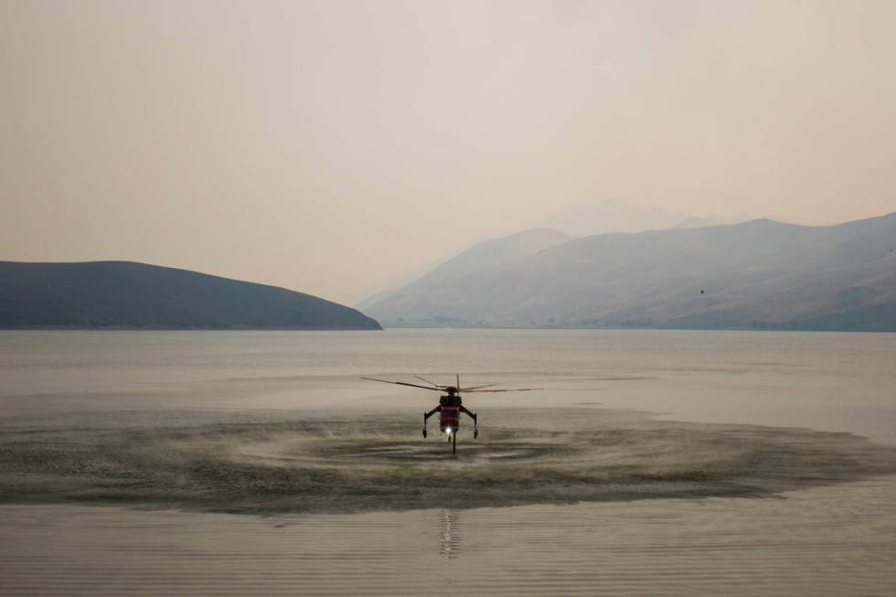 A firefighting helicopter is seen at Topaz Lake, in Nevada, Friday, July 23, 2021, while the T ...