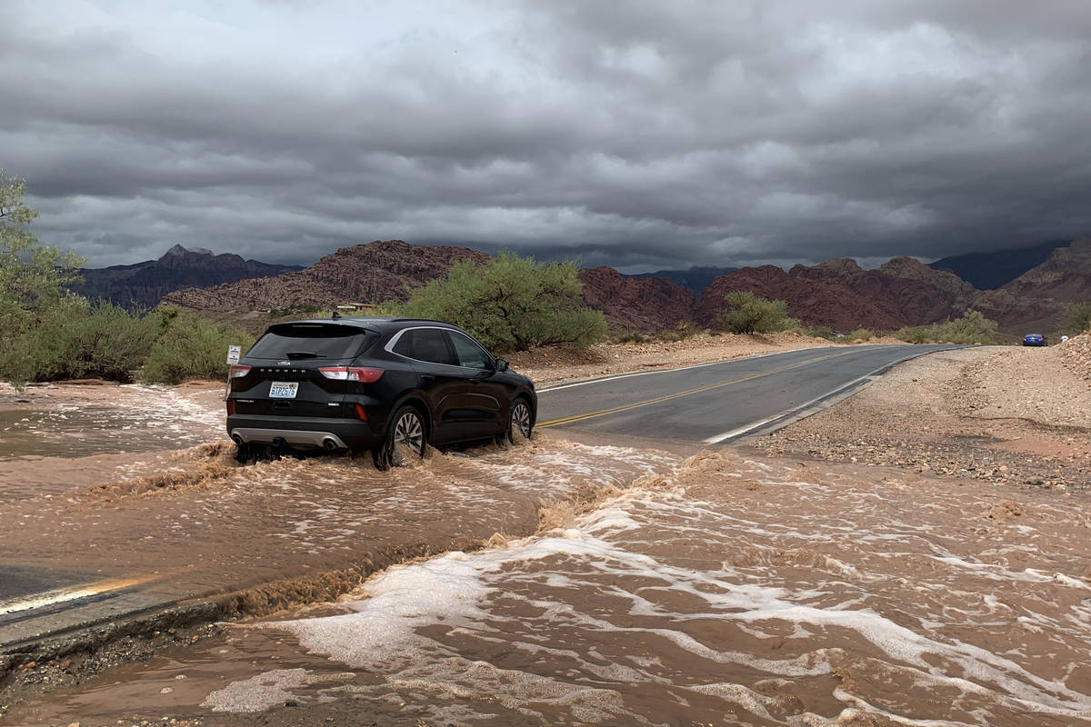 A vehicle drives through a flooded section of Calico Basin Road near Red Rock Canyon National C ...