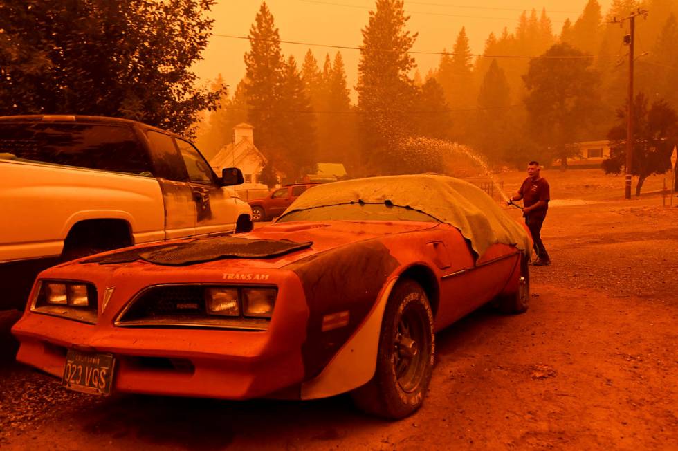 William Deal wets down his 1977 Trans Am as the Dixie Fire approaches Crescent Mills in Plumas ...